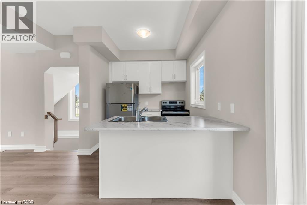 Kitchen featuring white cabinetry, stainless steel refrigerator, black range, and a breakfast bar with a light-toned countertop - 19 Picardy Drive Unit# 9, Hamilton, ON