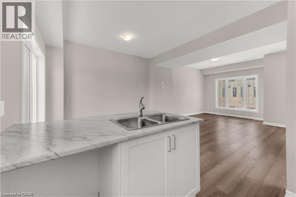 Kitchen island featuring a double basin stainless steel sink with a chrome faucet and a white marble-patterned countertop - 19 Picardy Drive Unit# 9, Hamilton, ON