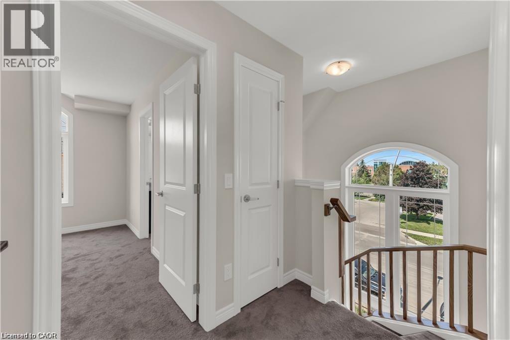 Upper-level hallway featuring neutral wall paint, dark grey carpet flooring, and white trim - 19 Picardy Drive Unit# 9, Hamilton, ON
