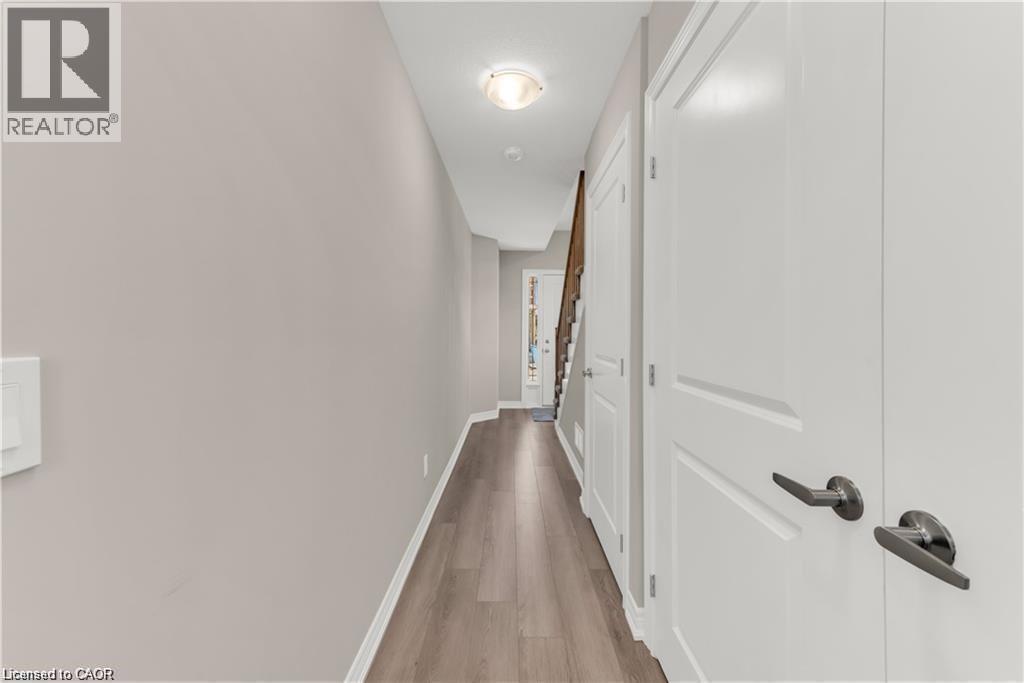 Hallway featuring wood-finish flooring, light neutral wall paint, and white trim - 19 Picardy Drive Unit# 9, Hamilton, ON
