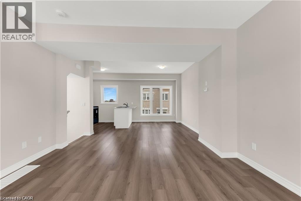 Expansive living area featuring wood-finish flooring, light neutral wall tones, recessed lighting, and white baseboards - 19 Picardy Drive Unit# 9, Hamilton, ON