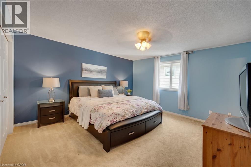 Carpeted bedroom featuring a window with vertical blinds, a ceiling-mounted light fixture, and a white interior door - 409 Jacqueline Boulevard, Hamilton, ON