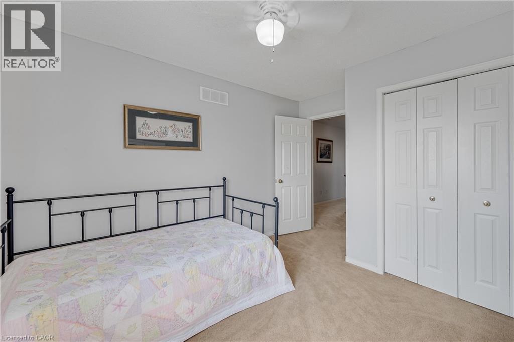 Carpeted room featuring light gray walls, a white ceiling fan with integrated lighting, and white bi-fold closet doors - 409 Jacqueline Boulevard, Hamilton, ON