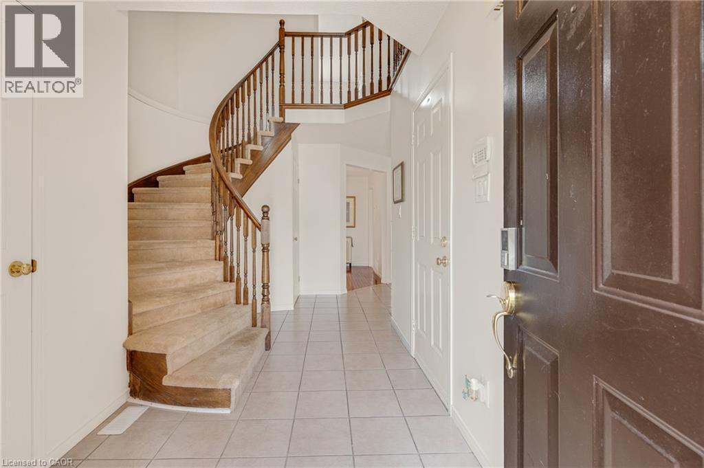 Entryway featuring a curved staircase with wood banister and carpeted treads - 409 Jacqueline Boulevard, Hamilton, ON