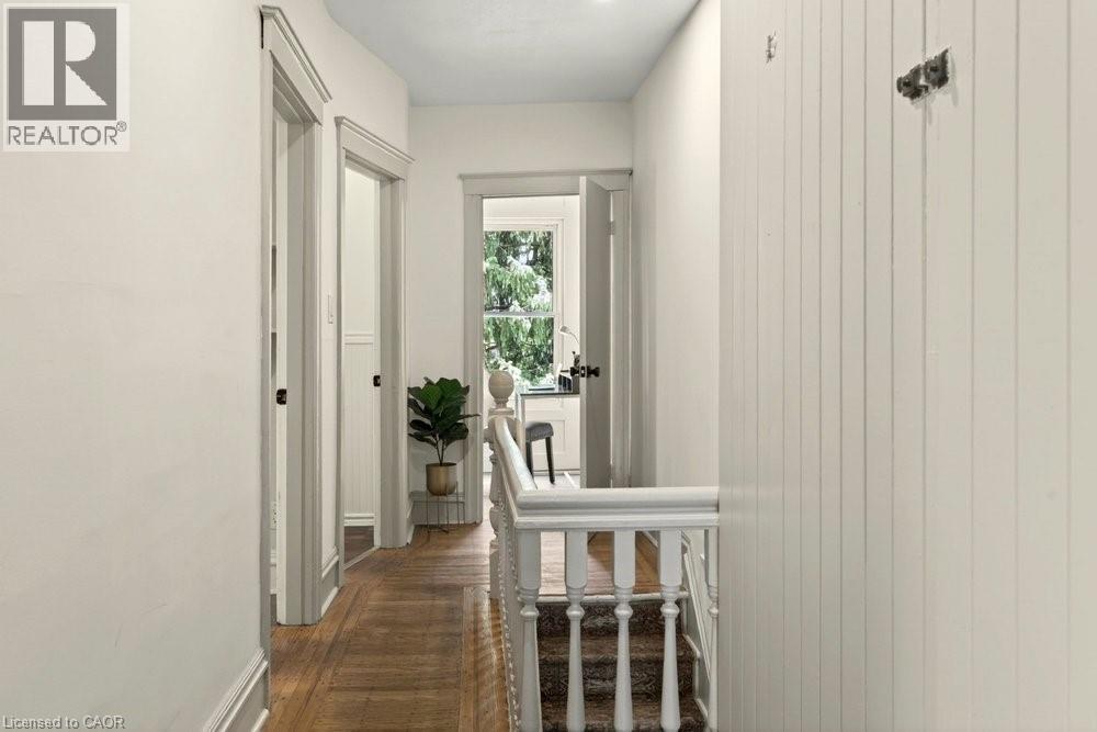 Hallway featuring wood-finish flooring, white paneled walls, and white painted trim - 148 Dundurn Street N, Hamilton, ON