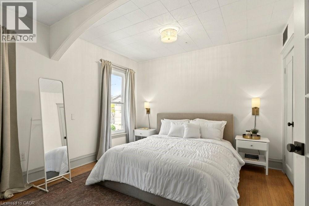 Room featuring wood-finish flooring, white walls, and a textured ceiling - 148 Dundurn Street N, Hamilton, ON