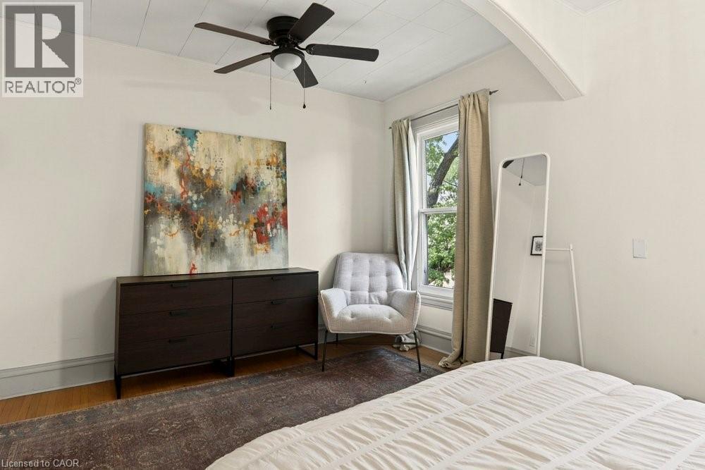 Room featuring light-toned walls, wood-finish flooring, and a ceiling fan - 148 Dundurn Street N, Hamilton, ON