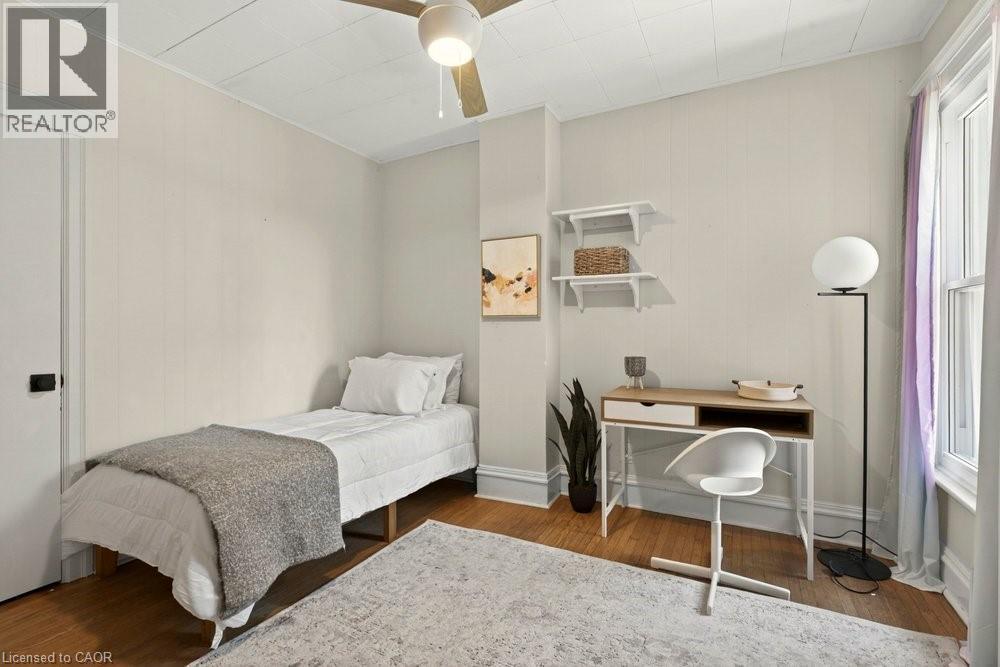 Room featuring wood-finish flooring, a neutral color palette, a window with natural light, and a ceiling fan with integrated lighting - 148 Dundurn Street N, Hamilton, ON