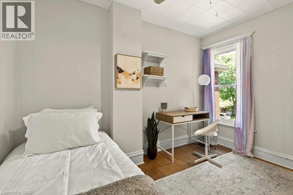 Room with wood-finish flooring, light-colored wall paneling, and a single window providing natural light - 148 Dundurn Street N, Hamilton, ON