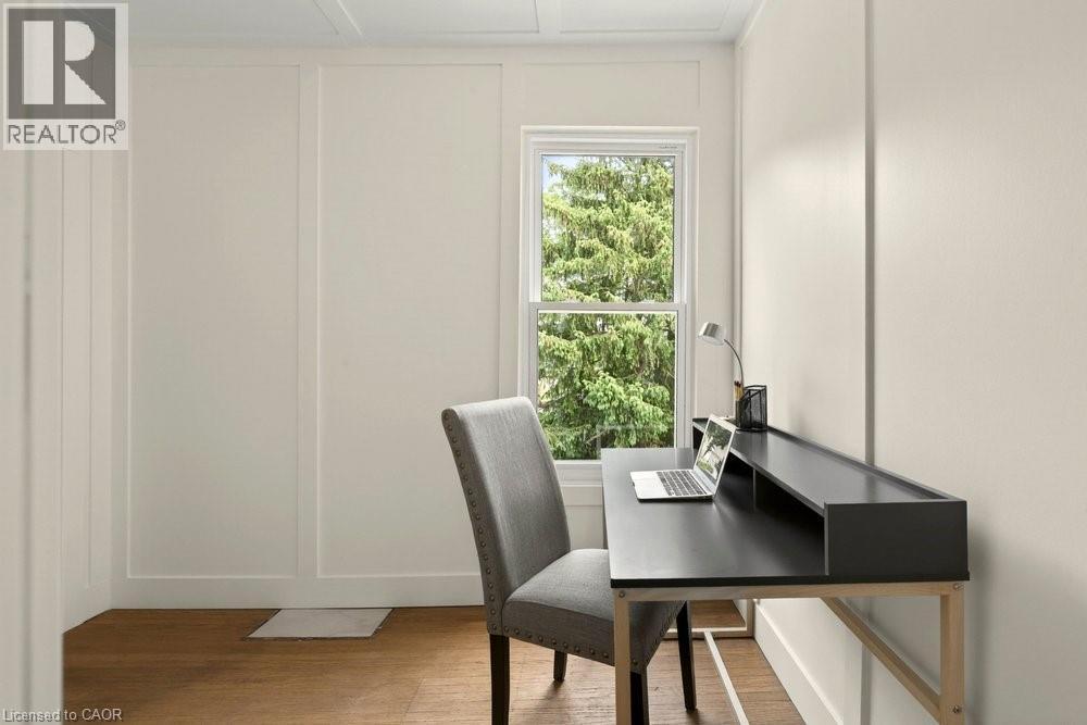 Room featuring light wood-finish flooring, a single window with white trim, and light-colored walls with board and batten detailing - 148 Dundurn Street N, Hamilton, ON