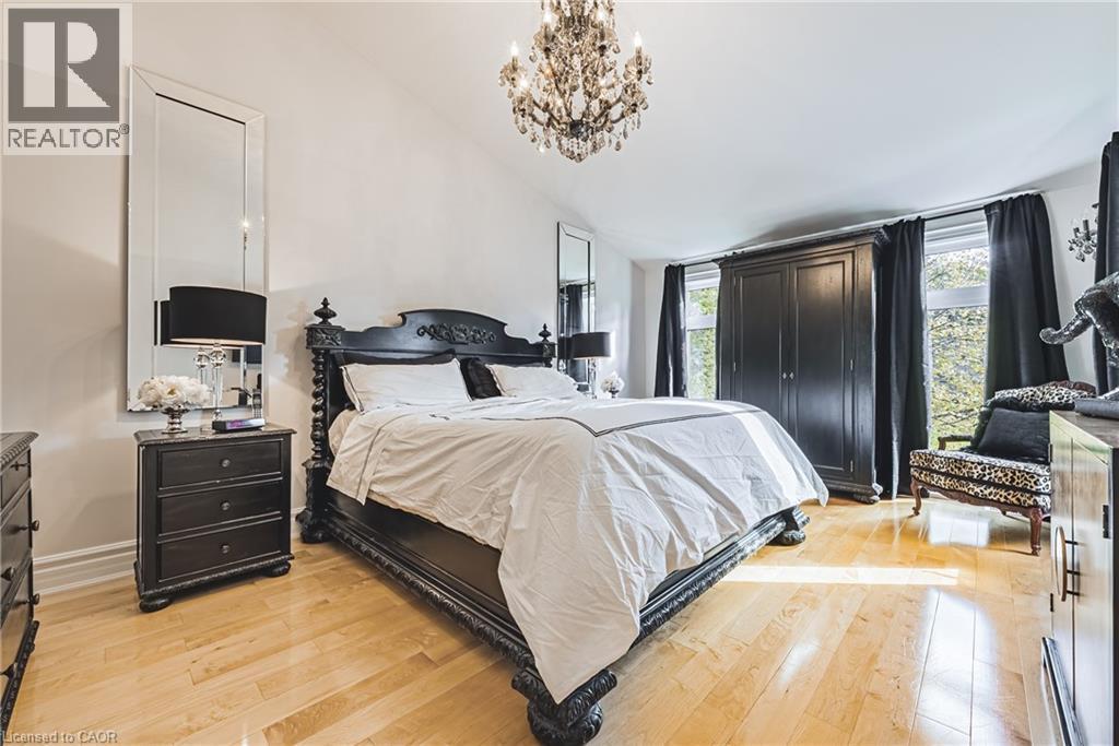 Bedroom featuring light wood-finish flooring, a crystal chandelier, and large windows with dark drapery - 712 Highvalley Road, Ancaster, ON