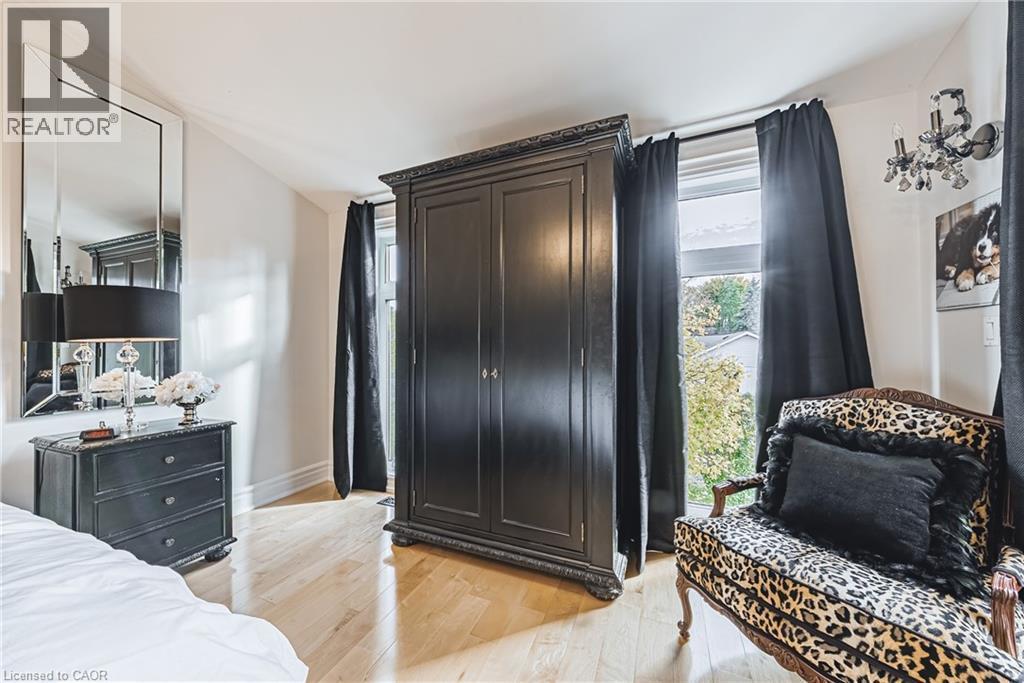 Bedroom featuring wood-finish flooring, white walls, and a large window with black drapes - 712 Highvalley Road, Ancaster, ON