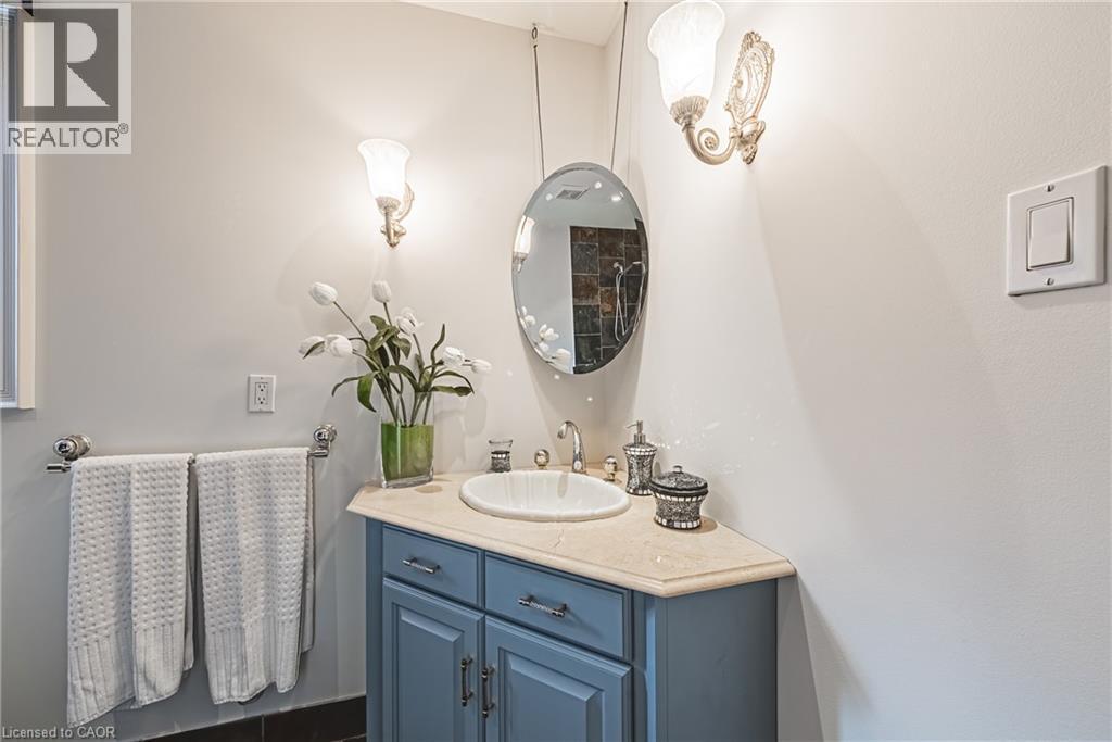 Bathroom vanity featuring a blue cabinet, integrated sink, and light-toned countertop - 712 Highvalley Road, Ancaster, ON