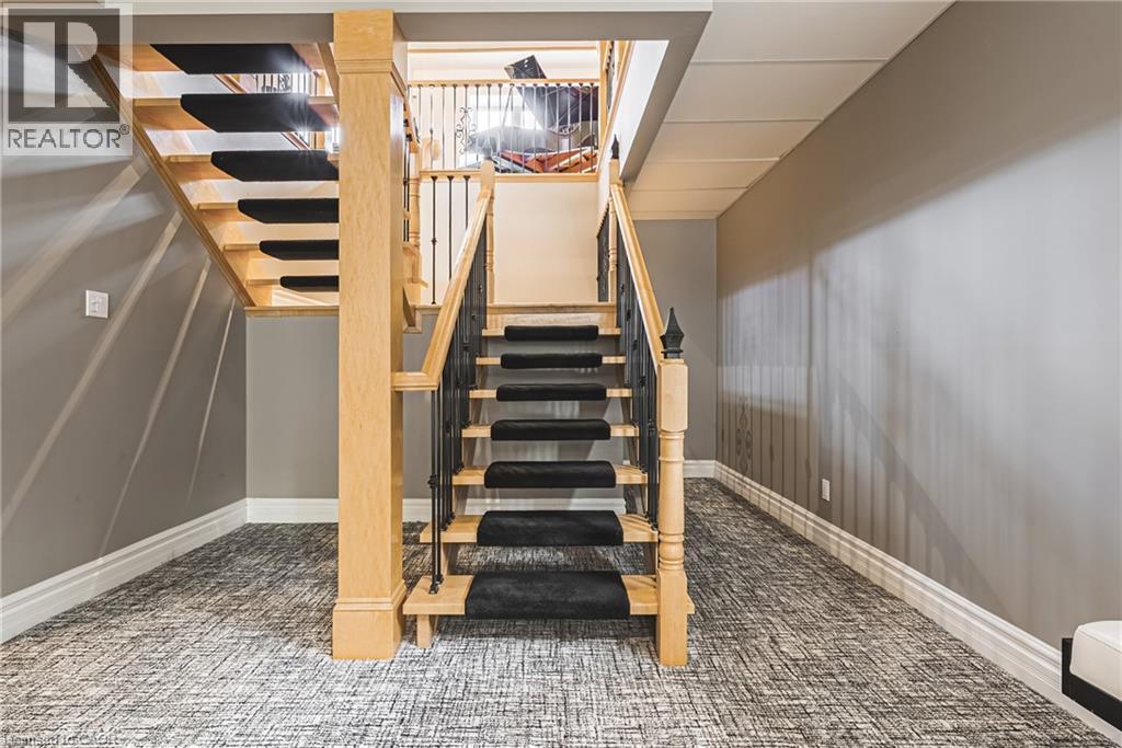 Hardwood staircase with black carpet risers and wrought iron balusters - 712 Highvalley Road, Ancaster, ON