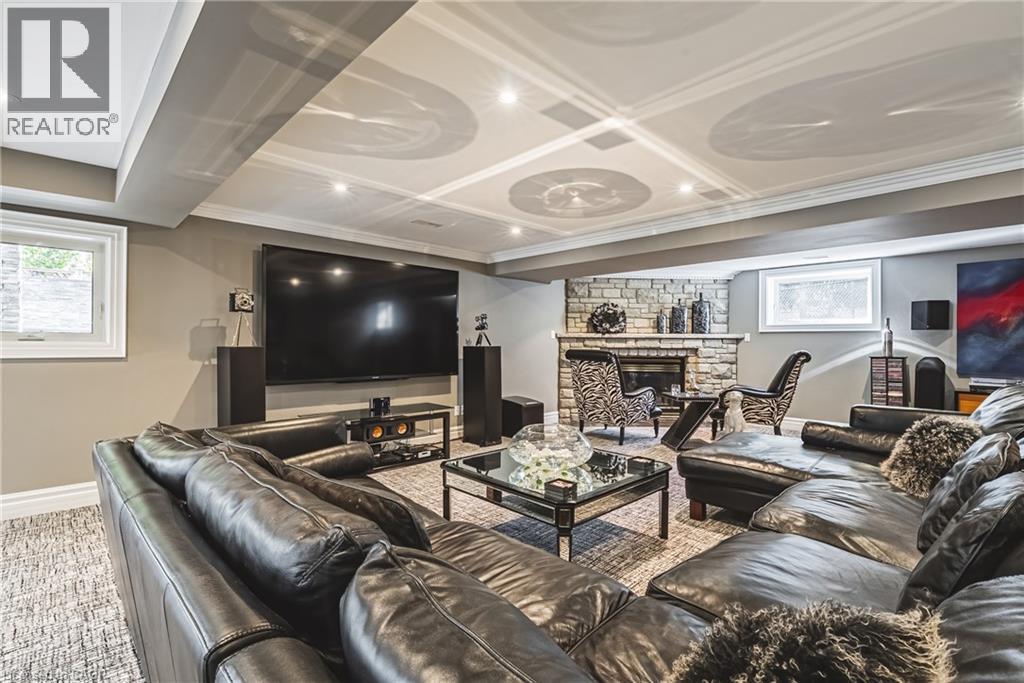 Finished lower level featuring a stone-clad fireplace and a coffered ceiling with recessed lighting - 712 Highvalley Road, Ancaster, ON