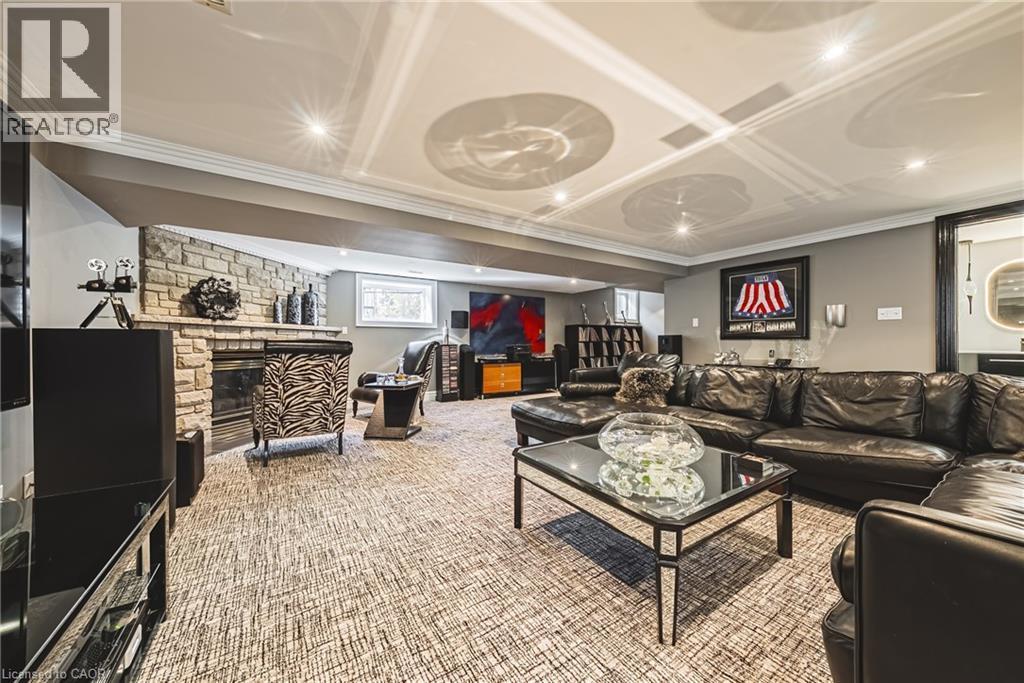 Spacious recreation room featuring a stone-clad fireplace, recessed lighting, crown molding, a patterned carpet, and a built-in wall niche - 712 Highvalley Road, Ancaster, ON