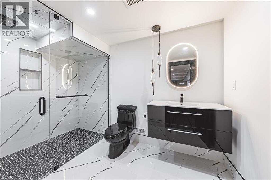 Contemporary bathroom featuring a floating vanity with a vessel sink, an illuminated oval mirror, and a frameless glass shower enclosure - 712 Highvalley Road, Ancaster, ON