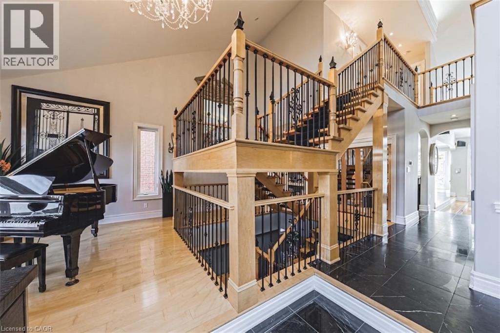 Grand foyer featuring a dual staircase with natural wood handrails and wrought iron balusters - 712 Highvalley Road, Ancaster, ON