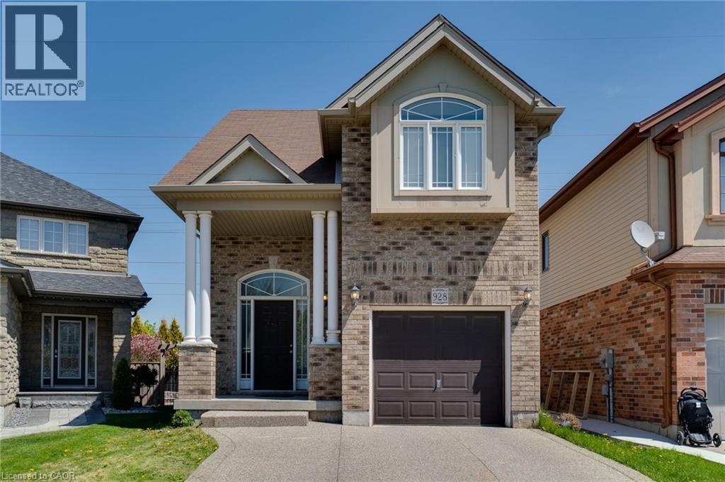 Brick facade residence featuring an arched portico with white columns, a dark panel garage door, a paved driveway, and an arched transom window above the main entry - 928 Dunblane Court, Kitchener, ON