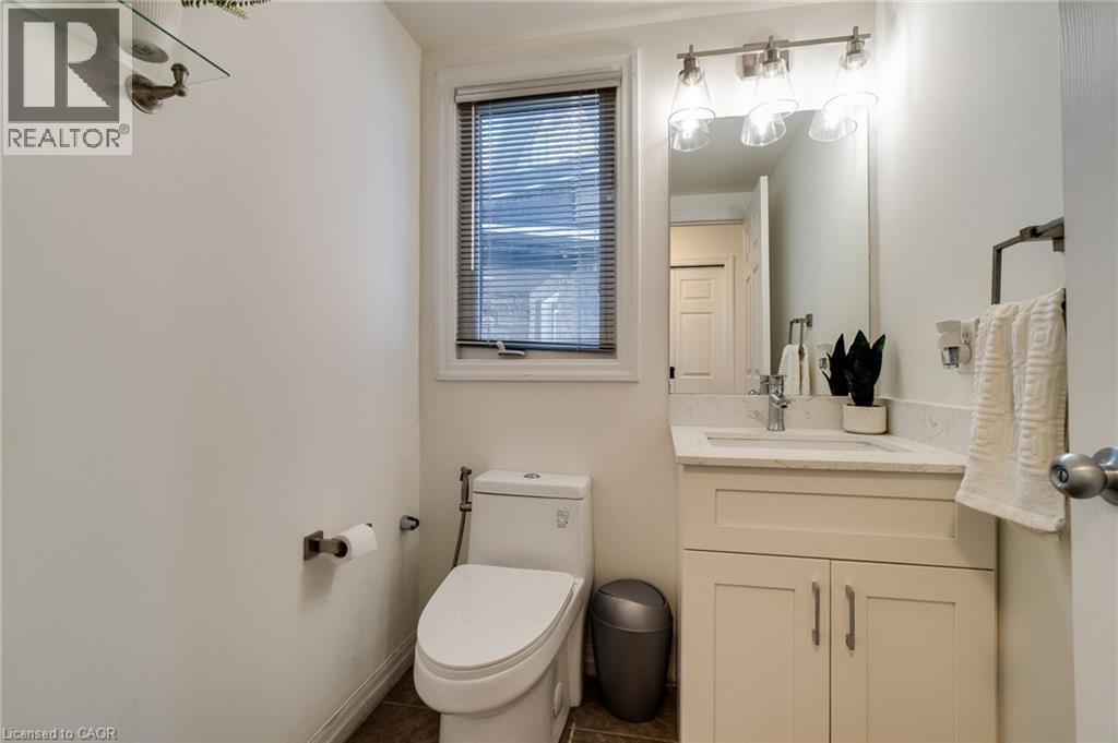 Bathroom featuring a single vanity with a white countertop and base cabinetry, brushed nickel hardware, an integrated sink, and an overhead vanity light fixture - 928 Dunblane Court, Kitchener, ON