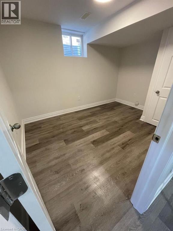 Room featuring wood-finish flooring, white baseboards, and a window with blinds - 928 Dunblane Court, Kitchener, ON