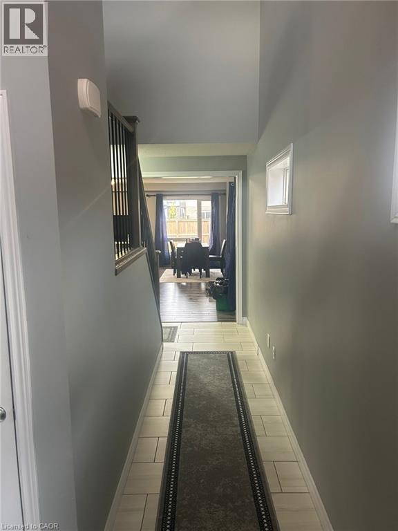 Hallway featuring light-toned rectangular floor tiles, neutral wall paint, and white baseboards - 766 Freeport Street, London, ON