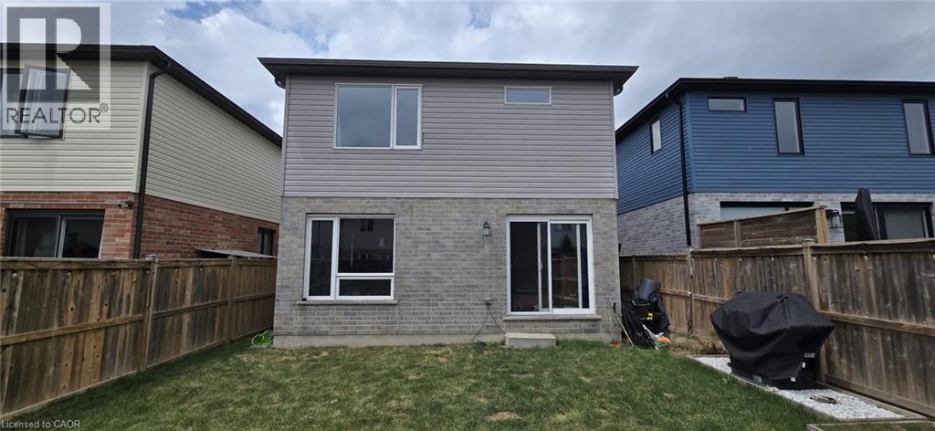 Rear exterior featuring a manicured lawn, full privacy fencing, and a combination of brick and siding finishes - 766 Freeport Street, London, ON
