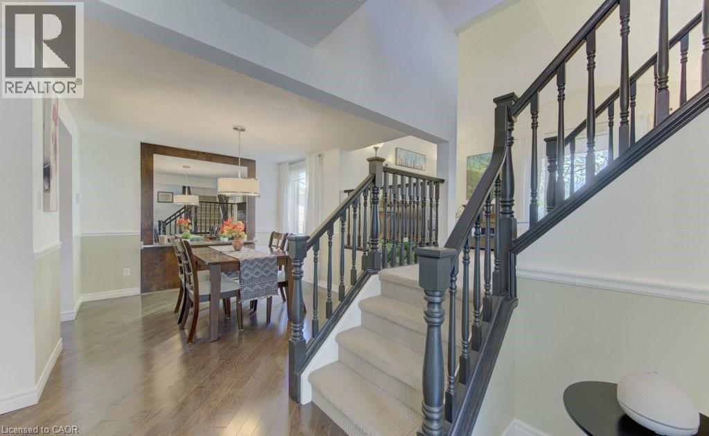 Foyer with carpeted staircase featuring dark wood balusters and handrail, complemented by wood-finish flooring - 108 Clearwater Crescent, Waterloo, ON