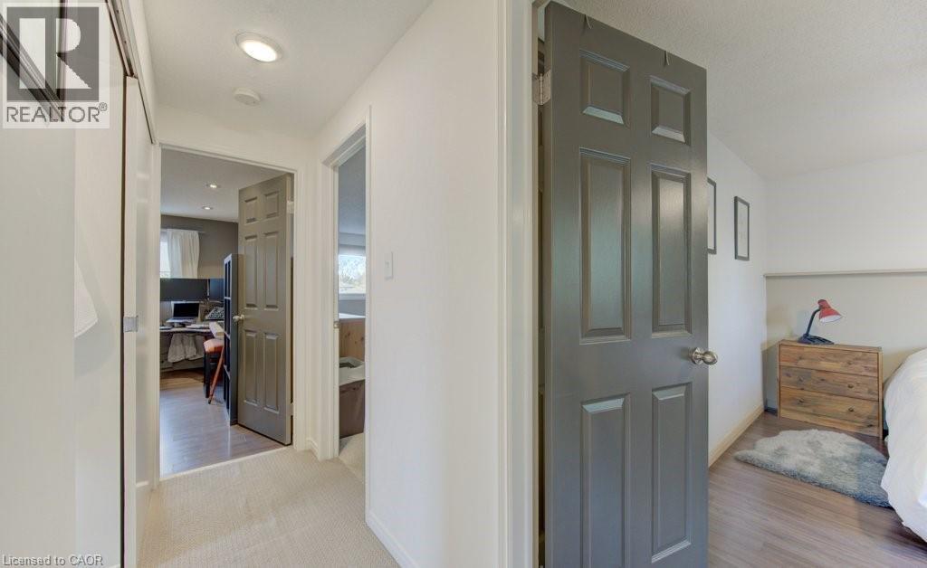Hallway featuring light carpeting, recessed lighting, white walls, and a dark paneled door - 108 Clearwater Crescent, Waterloo, ON