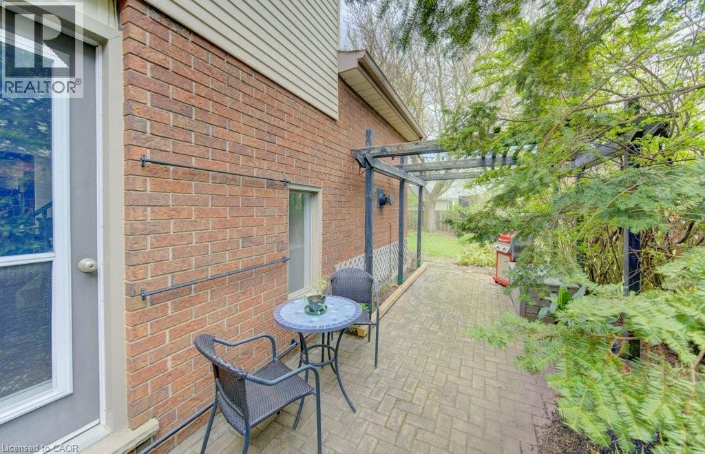 Brick exterior with a side patio featuring a paver stone surface, an outdoor pergola structure, and mature landscaping - 108 Clearwater Crescent, Waterloo, ON