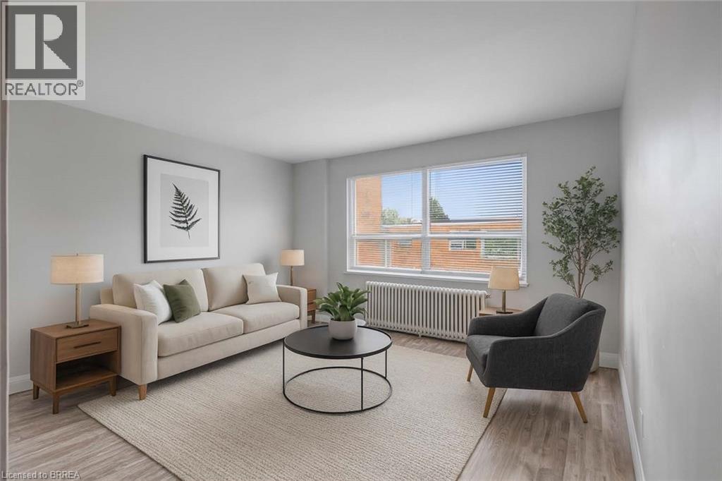 Virtually staged Living room featuring and laminate flooring and large window - 57 Mericourt Road Unit# 310, Hamilton, ON