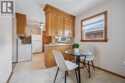 Kitchen with white appliances, light countertops, backsplash, ceiling fan, and a peninsula - 