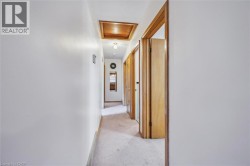 Hallway featuring light carpet and attic access - 