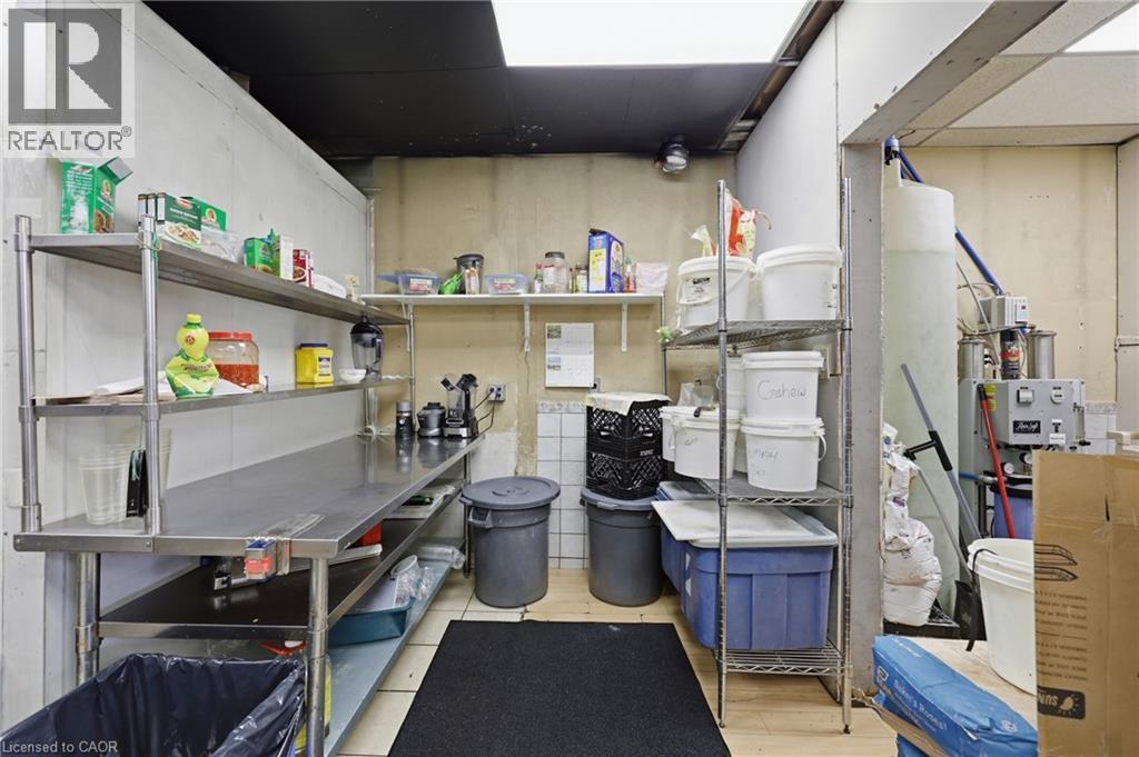 Commercial kitchen area featuring stainless steel work surfaces, industrial shelving, and a concrete floor - 239 York Boulevard, Hamilton, ON