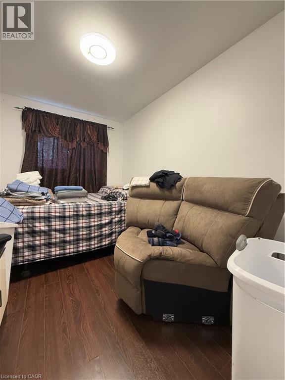 Room featuring wood-finish flooring, white walls, and a window with dark drapery - 181 Thaler Avenue, Kitchener, ON