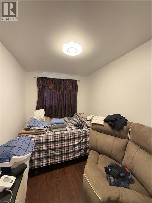 Interior room featuring wood-finish flooring, white walls, and a window with dark fabric drapes - 181 Thaler Avenue, Kitchener, ON