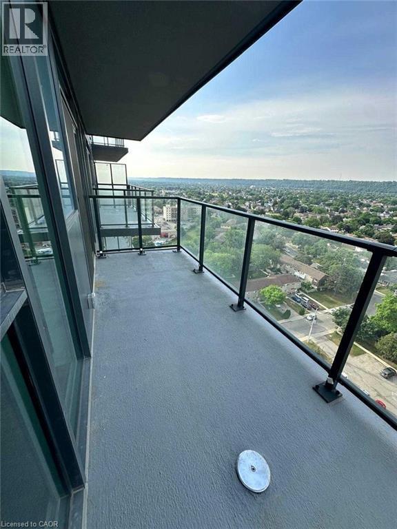 Expansive balcony featuring a textured concrete surface, clear glass railing with black posts, and broad cityscape scenery - 2782 Barton Street E, Hamilton, ON