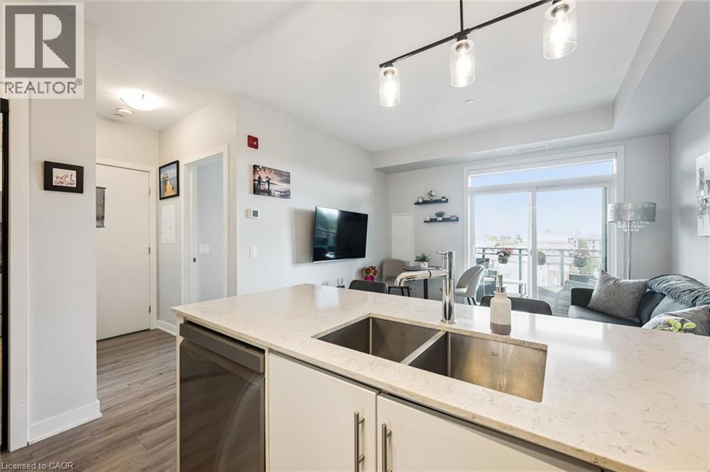 Kitchen island featuring a double basin stainless steel sink, a chrome faucet, and a light-toned countertop - 340 Plains Road E Unit# 507, Burlington, ON - Indoor Photo Showing Kitchen With Double Sink