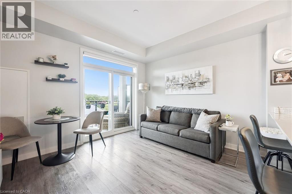 Living area featuring wood-finish flooring and a sliding glass door to an outdoor space - 340 Plains Road E Unit# 507, Burlington, ON - Indoor Photo Showing Living Room