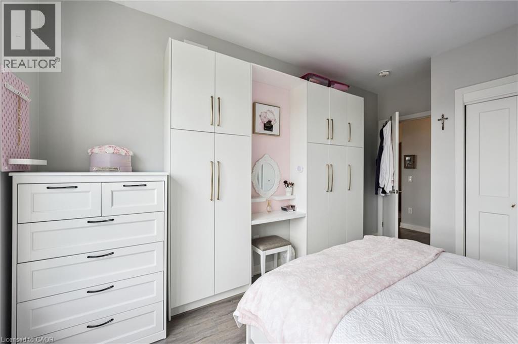 White built-in cabinetry with brushed nickel hardware, integrated vanity area, and light-toned wood-finish flooring - 340 Plains Road E Unit# 507, Burlington, ON - Indoor Photo Showing Bedroom