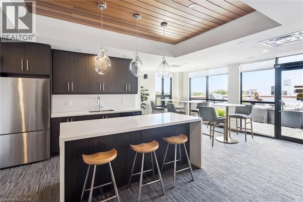 Kitchen area featuring dark wood-finish cabinetry and a white countertop island - 340 Plains Road E Unit# 507, Burlington, ON - Indoor Photo Showing Kitchen With Stainless Steel Kitchen With Upgraded Kitchen