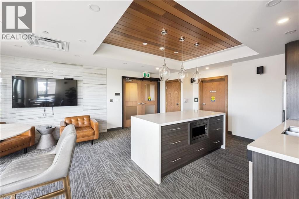 Open-concept living area featuring a central island with integrated microwave, pendant lighting, and wood-panel ceiling accents - 340 Plains Road E Unit# 507, Burlington, ON - Indoor