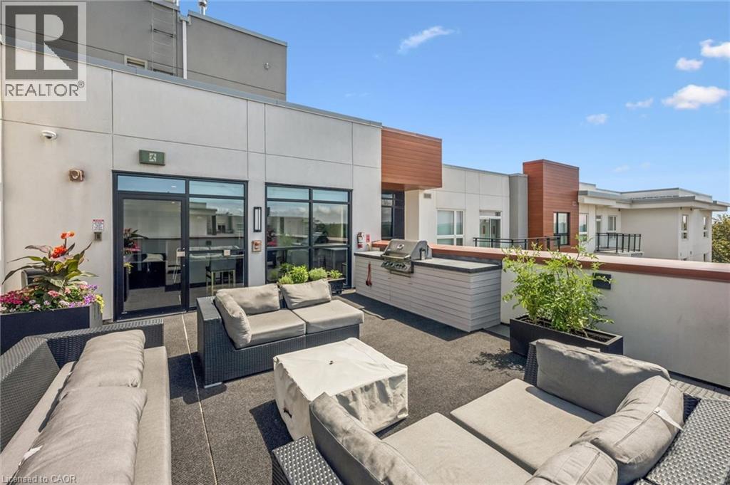 Expansive rooftop patio featuring an integrated built-in grill station, dark-toned flooring, and direct access to interior spaces through large glass doors - 340 Plains Road E Unit# 507, Burlington, ON - Outdoor