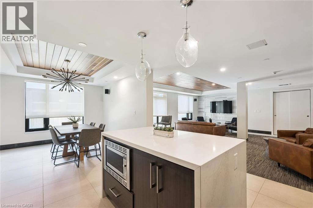 Open-concept room featuring a white countertop island with integrated microwave, wood-finish flooring, recessed lighting, and a coffered ceiling with wood paneling - 340 Plains Road E Unit# 507, Burlington, ON - Indoor
