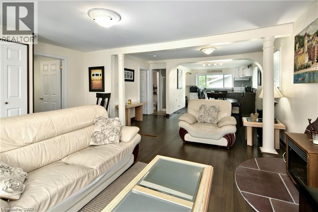Open-concept living area featuring dark wood-finish flooring, white trim, recessed ceiling lights, and architectural columns - 42 5Th Lane, Wasaga Beach, ON - Indoor Photo Showing Living Room