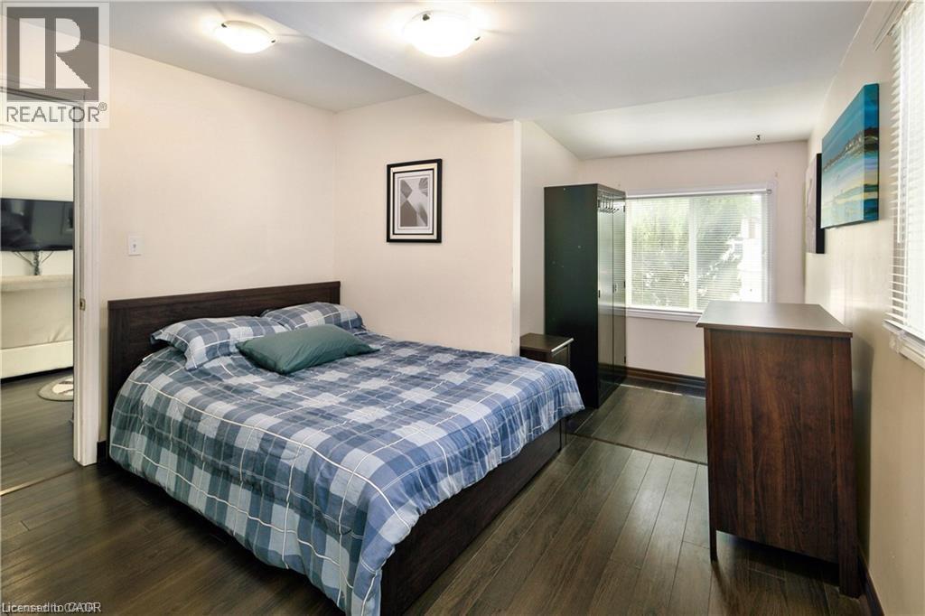 Bedroom with dark wood-finish flooring, a white ceiling with flush-mount lighting, and a single window with white blinds - 42 5Th Lane, Wasaga Beach, ON - Indoor Photo Showing Bedroom