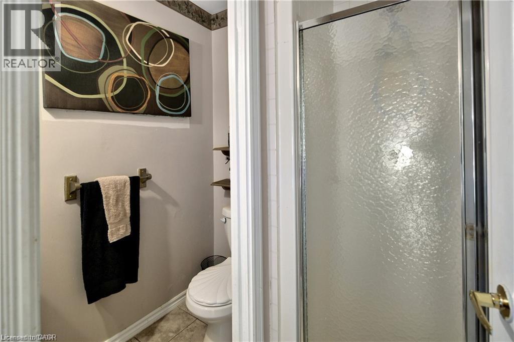 Enclosed shower with frosted glass door, adjacent to a toilet and wall-mounted towel bar - 42 5Th Lane, Wasaga Beach, ON - Indoor Photo Showing Bathroom