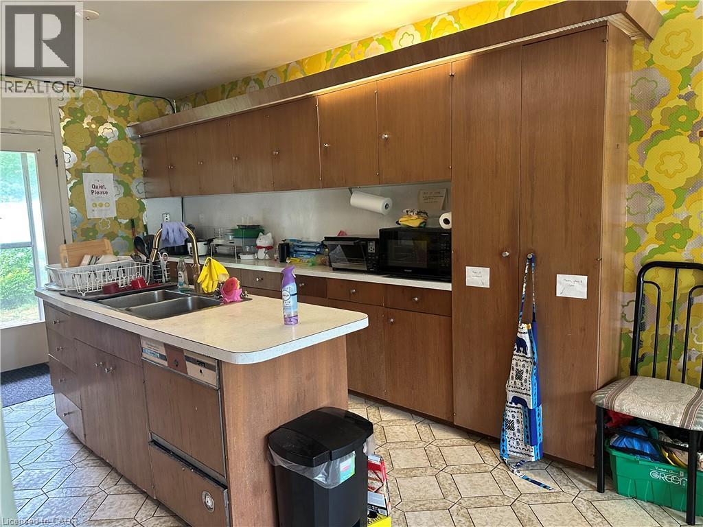 Kitchen featuring extensive wood cabinetry, an island with a double basin sink, and an integrated dishwasher - 11 Wilmont Court, Hamilton, ON