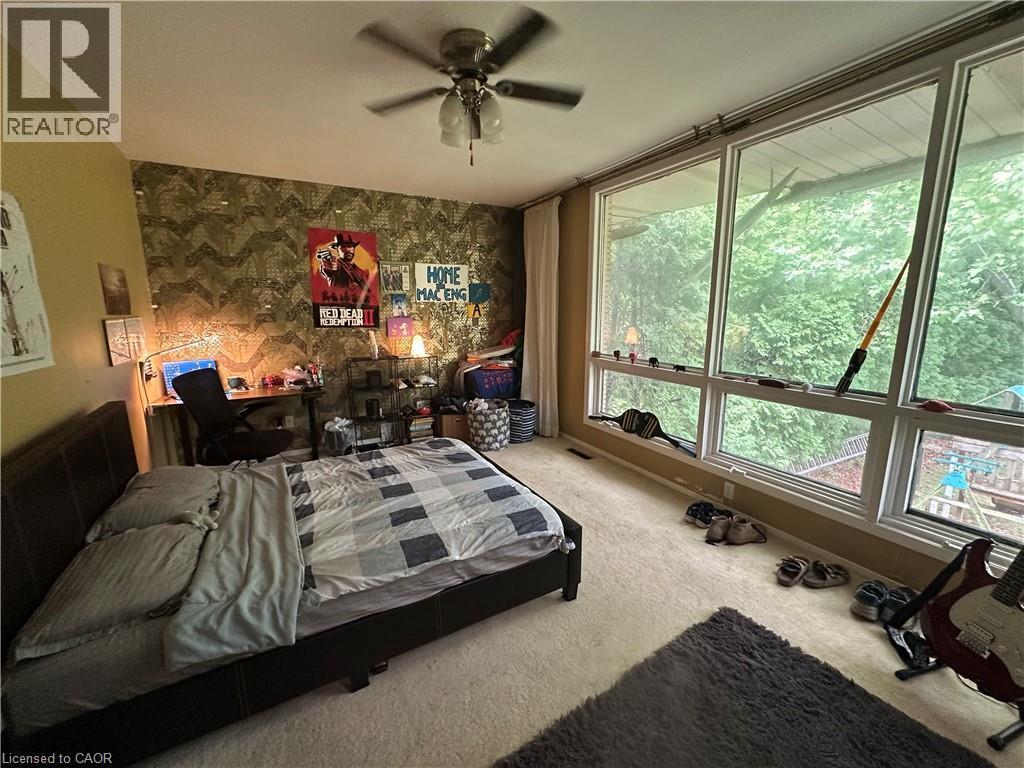 Spacious room featuring a full wall of floor-to-ceiling windows, soft wall-to-wall carpeting, and a ceiling fan - 11 Wilmont Court, Hamilton, ON