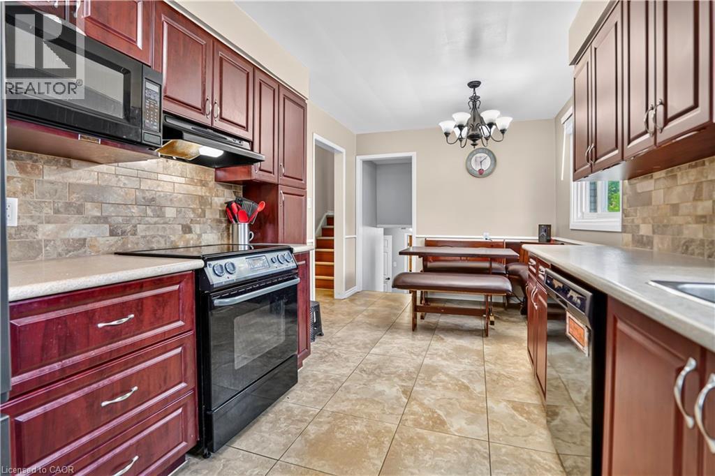 Kitchen featuring cherry-stained cabinetry, light-toned countertops, a tile backsplash, and tile flooring - 234 Thunderbird Drive, Cambridge, ON - Indoor Photo Showing Kitchen